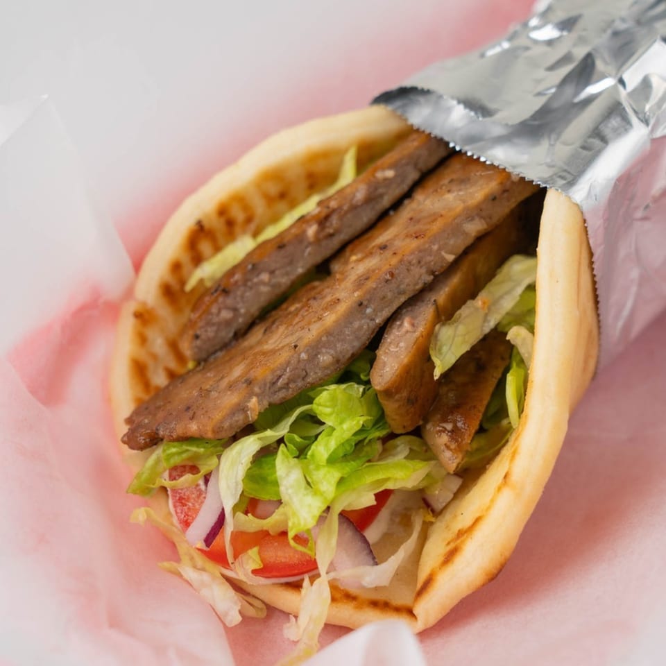 A TJ's Pizza & Wings gyro, with meat, lettuce, tomatoes, and onions in pita bread.
