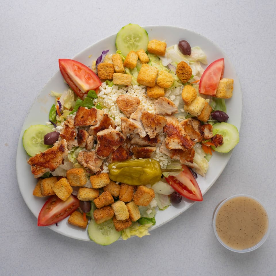 TJ's Pizza & Wings' grilled chicken salad with croutons, feta, tomatoes, cucumbers, olives, and dressing.